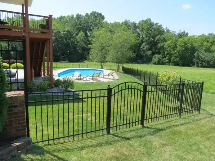 Black aluminum fence with an arched walk gate on a sloped backyard leading to a pool in Louisville, Kentucky