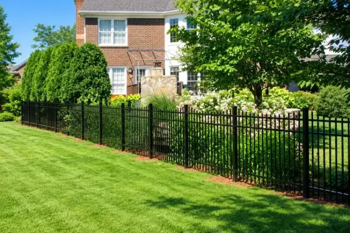 Black aluminum fence along a planted bed beside a brick home in Louisville, Kentucky